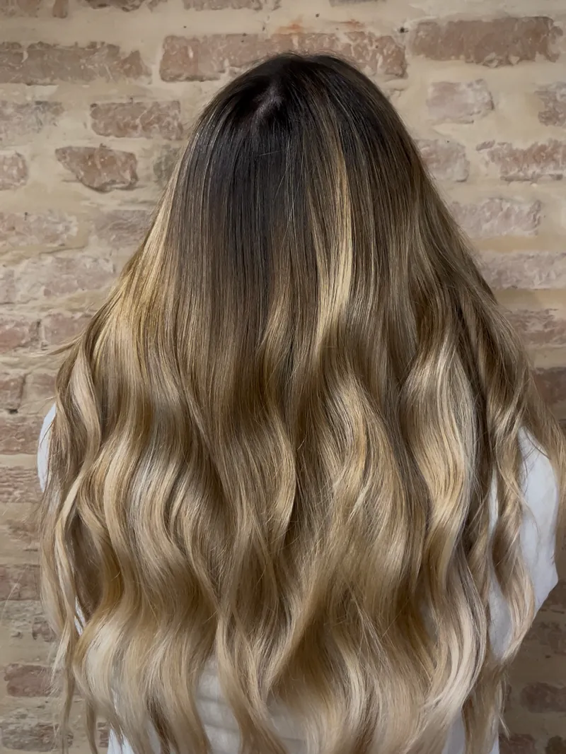 Capelli lunghi con radici scure e lunghezze bionde mosse, visti da dietro