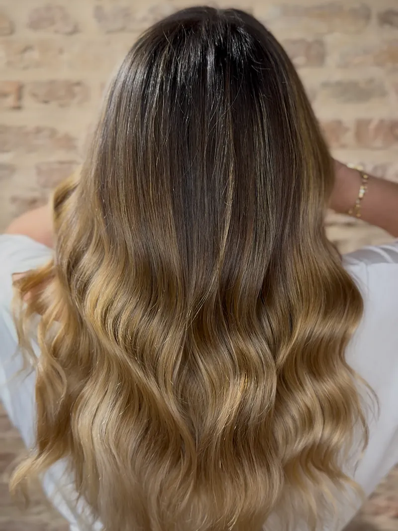 Schiariture bionde su capelli mossi di media lunghezza, viste da dietro