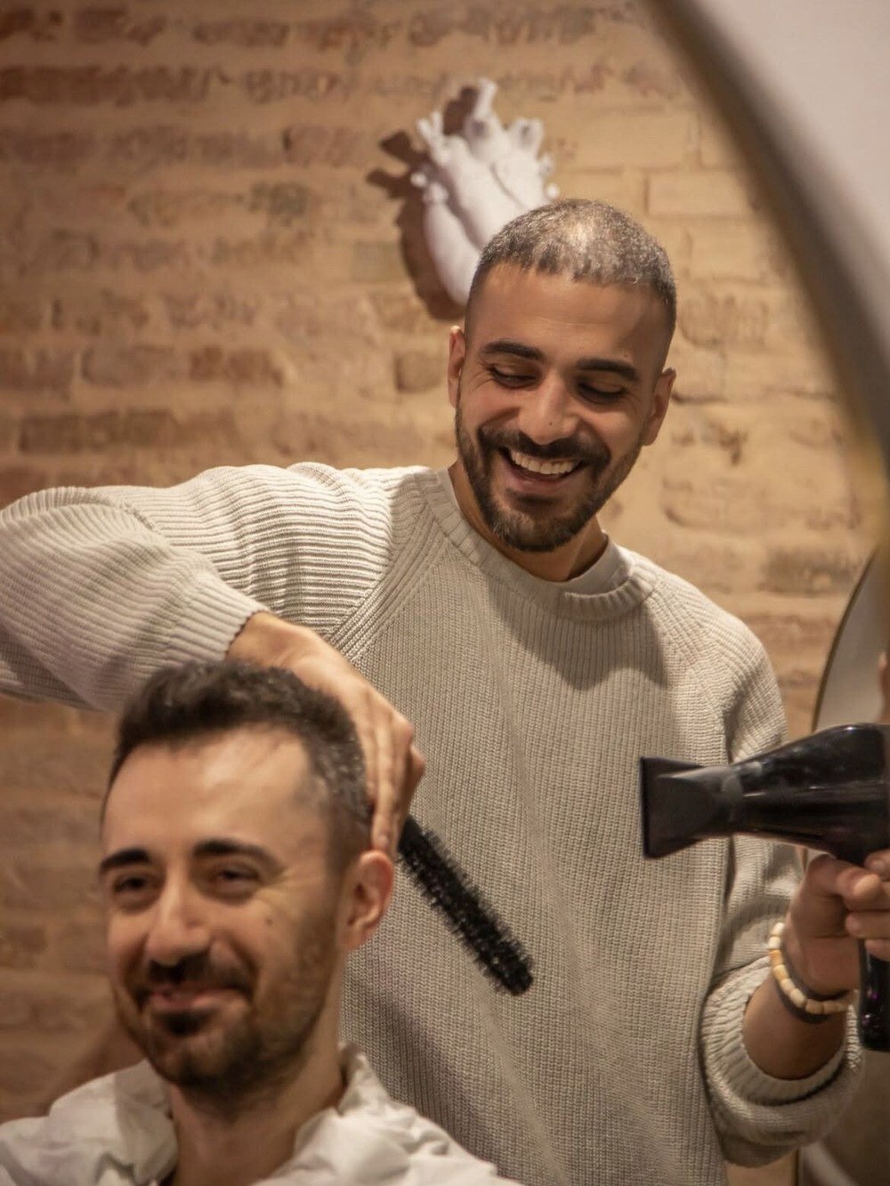 Enrico Cantore al lavoro con phon e spazzola su un cliente