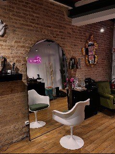 Zona di attesa del salone con poltrone e specchio ad arco