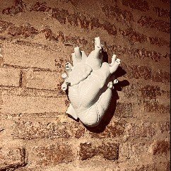 Dettaglio scultura a forma di cuore anatomico sulla parete in mattoni